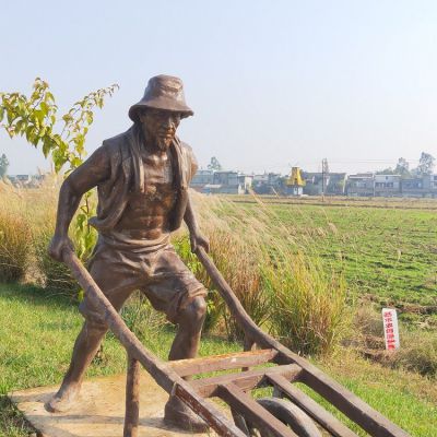 頭戴草帽，身穿坎肩，推獨(dú)輪車的老漢銅雕